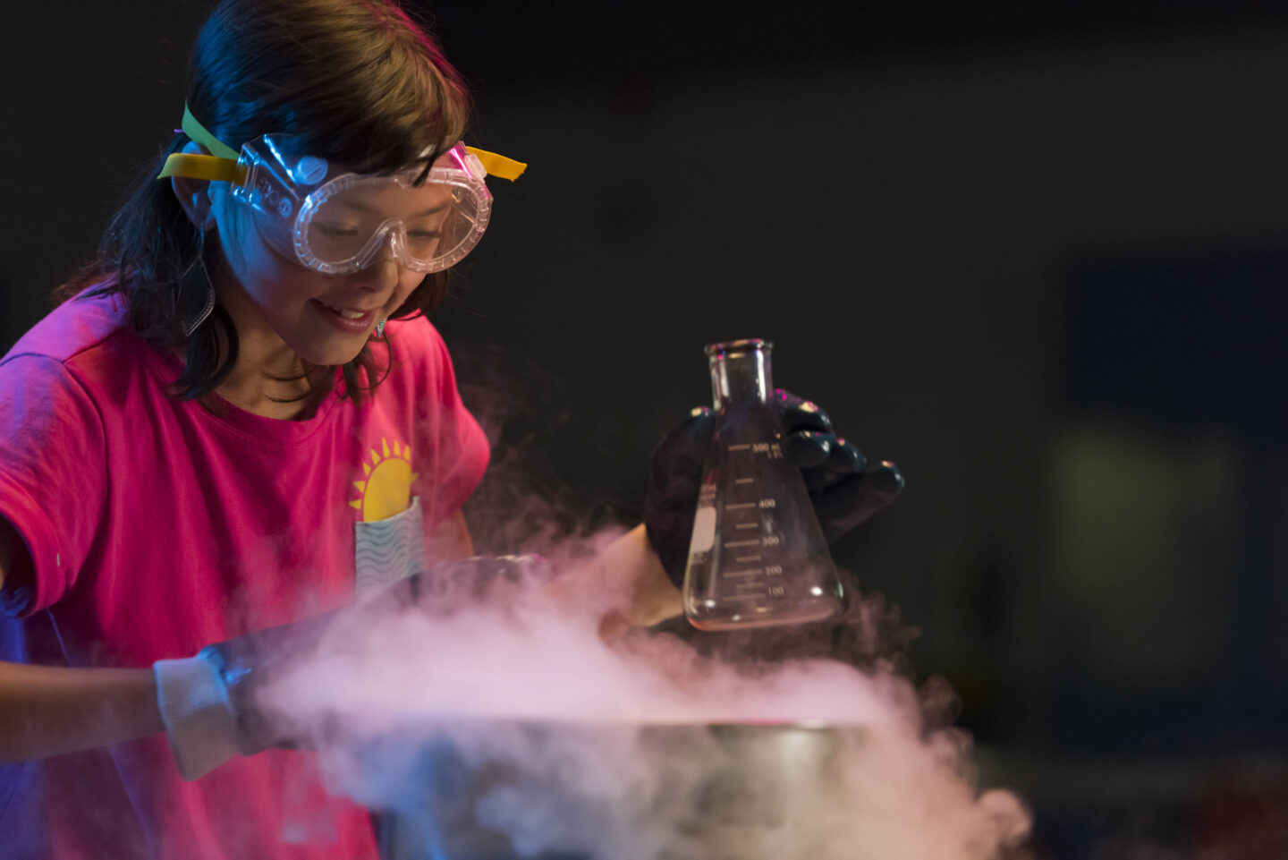 A young person holding a conical flask and peering into a smoky bowl.