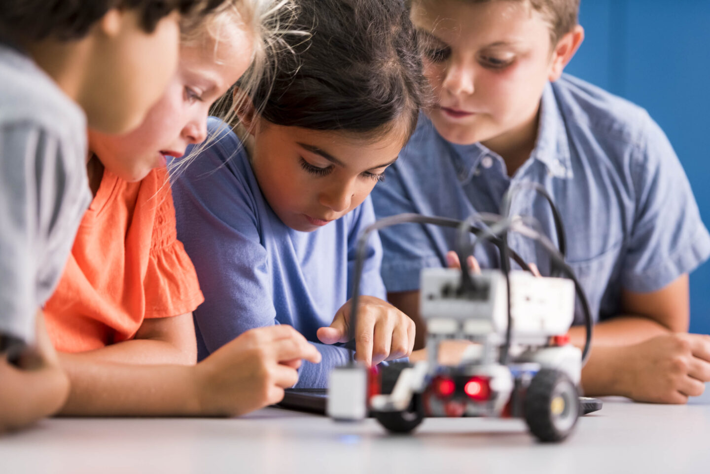 Four students are working on a project building a robot car