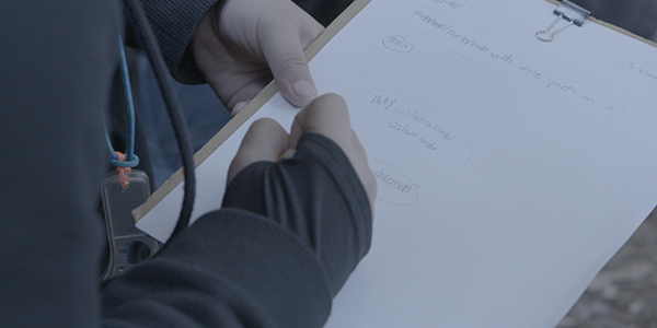 A student writes on a clipboard while conducting an outdoor science experiment in a schoolyard.