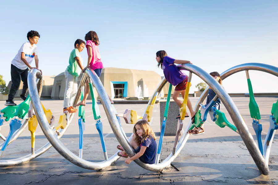 Children climbing on the DNA Sculpture on the plaza at The Lawrence
