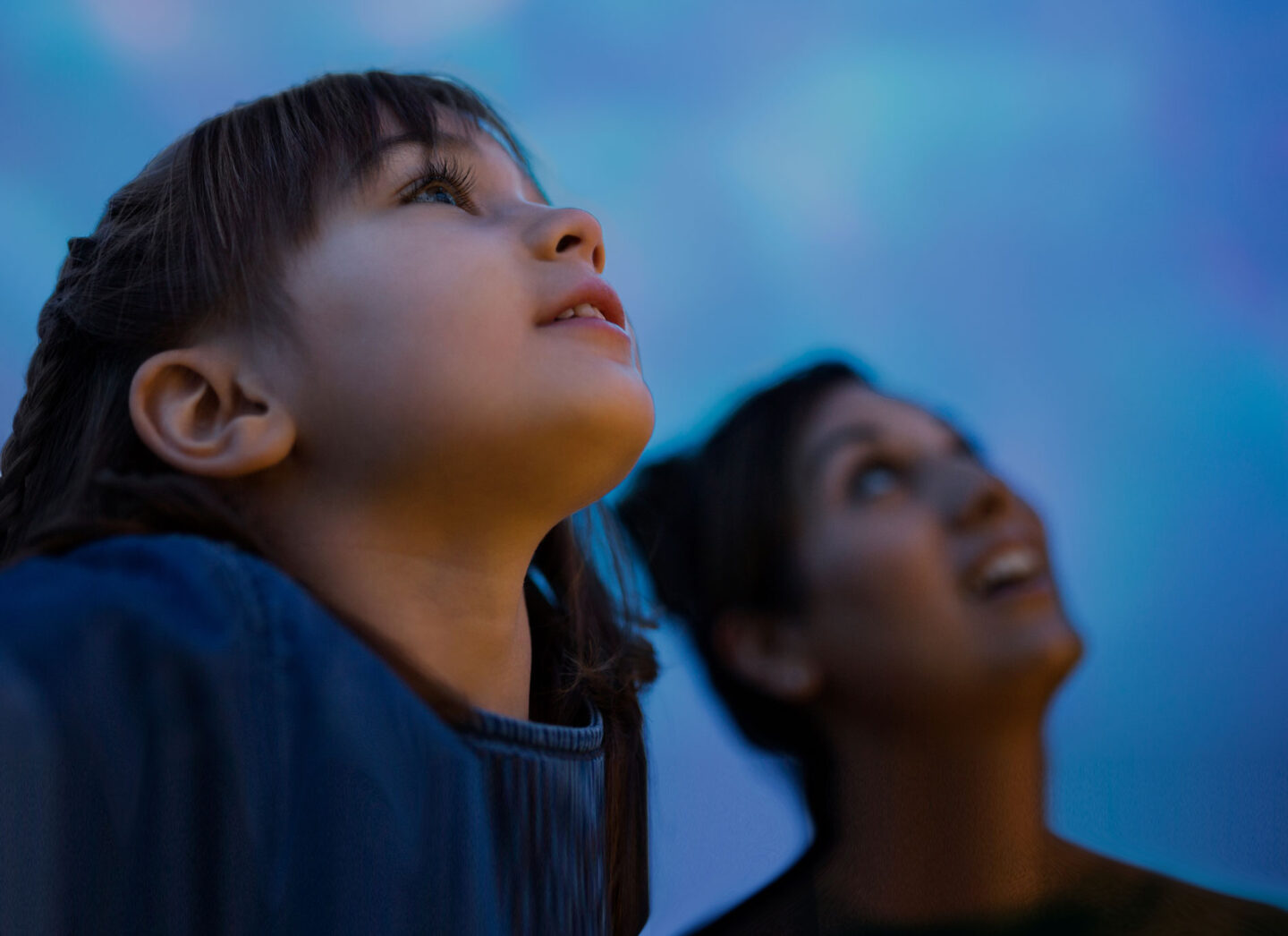 A child and an adult look up at the night sky