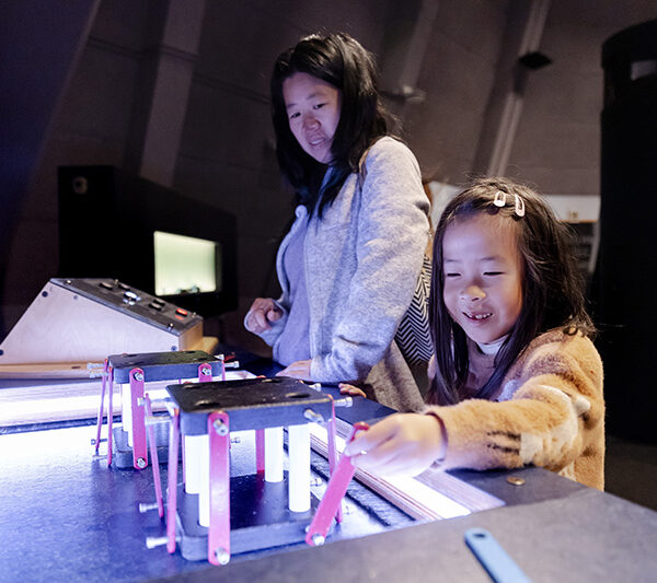 A visitor constructing a building to test on an earthquake shake table in Design Quest