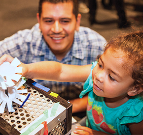 A child and an adult examining a science exhibit