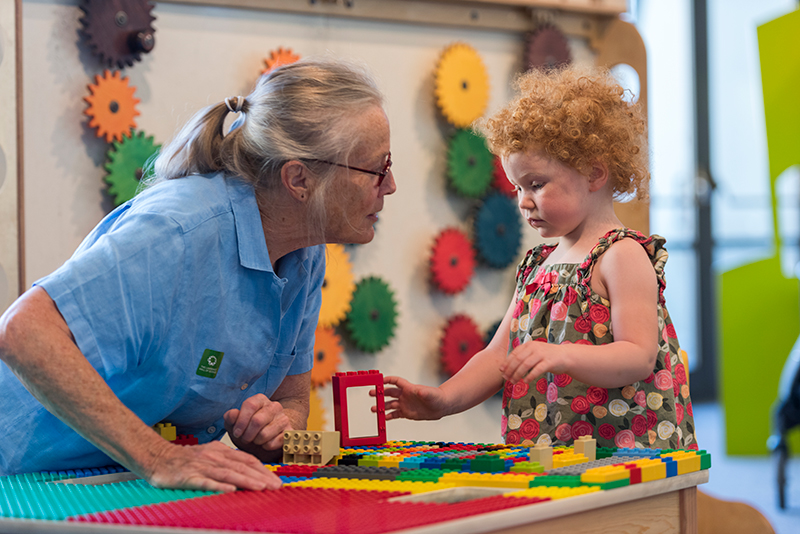An adult and child visitor collaborate to build a structure in the Young Explorers Area