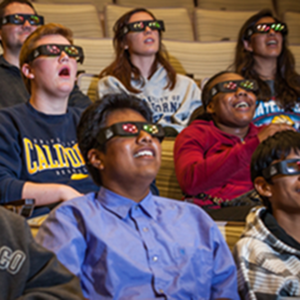 People watching a science film in the 3D theater wearing 3D glasses