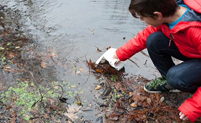 A young person examining a lake.