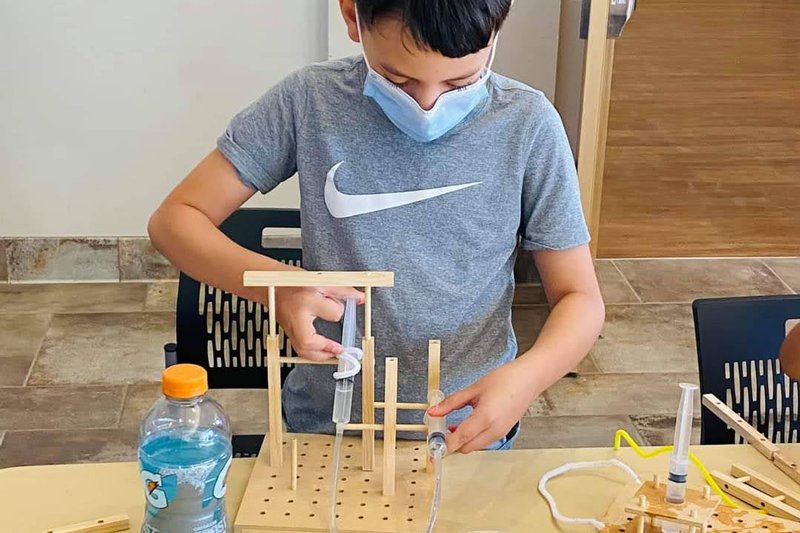 A student constructs an invention during the Make It Move workshop