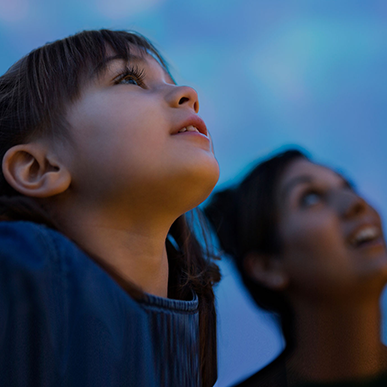 A child and an adult look up at the night sky